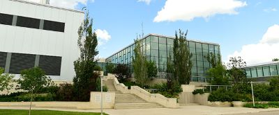 exterior of large glass building with lots of trees in front